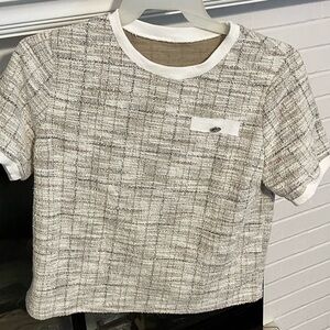 Short sleeved top with a woven style pattern in black, tan, white.